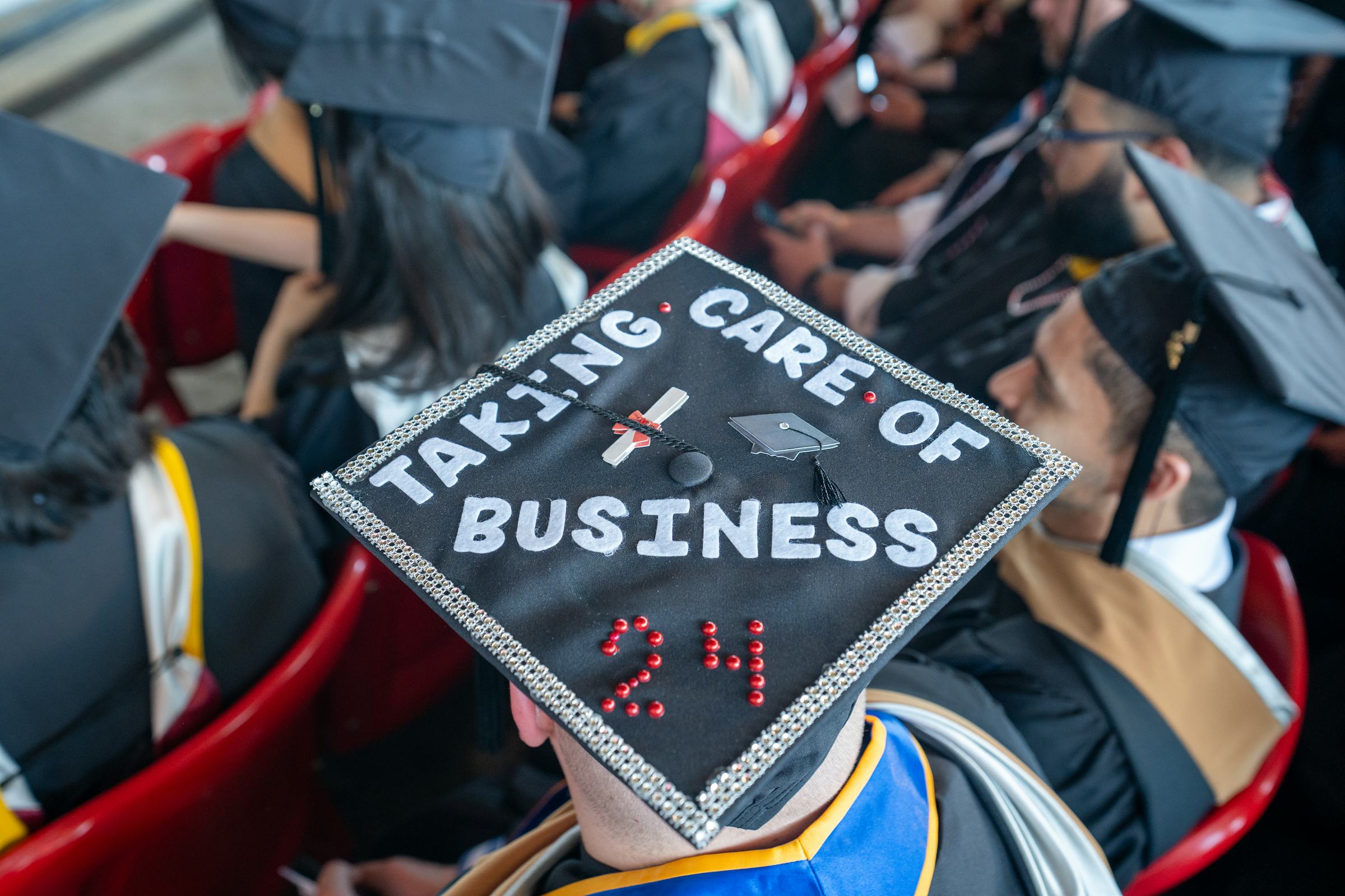 Back of the headshot of a graduation cap that says "Taking care of business 2024"