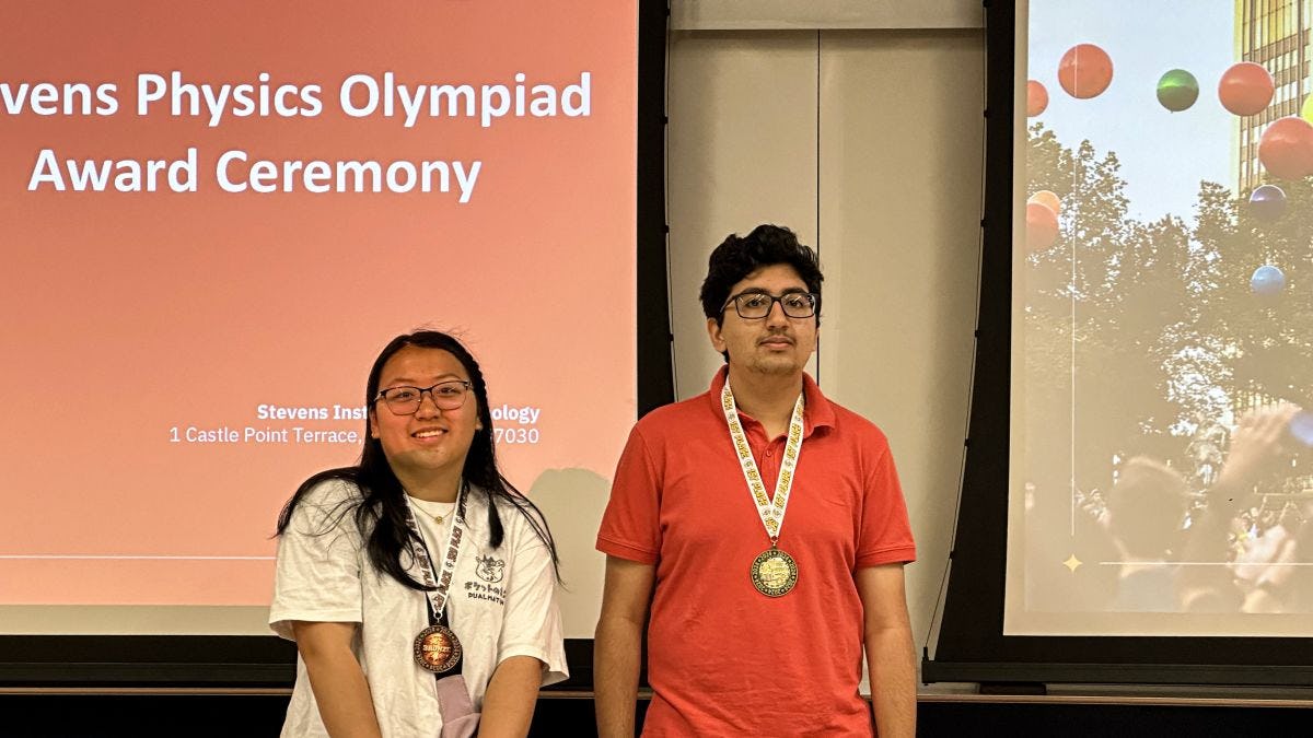 Two of the winners from the 2024 Physics Olympiad smiling with their medals.
