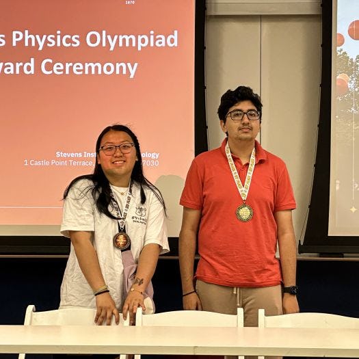 Two of the winners from the 2024 Physics Olympiad smiling with their medals.