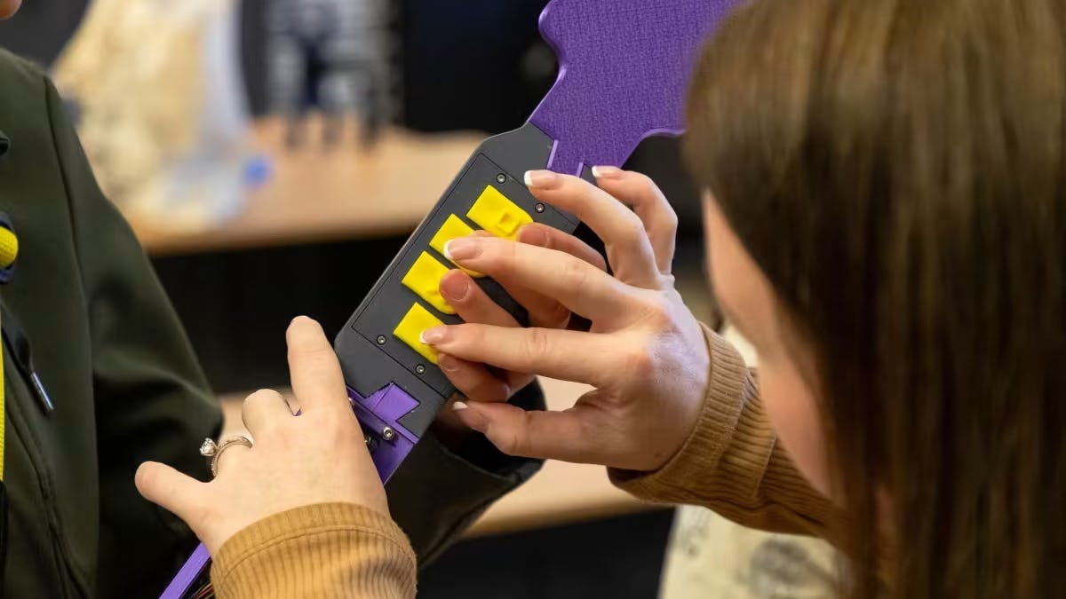 A close-up of hands playing on a toy guitar