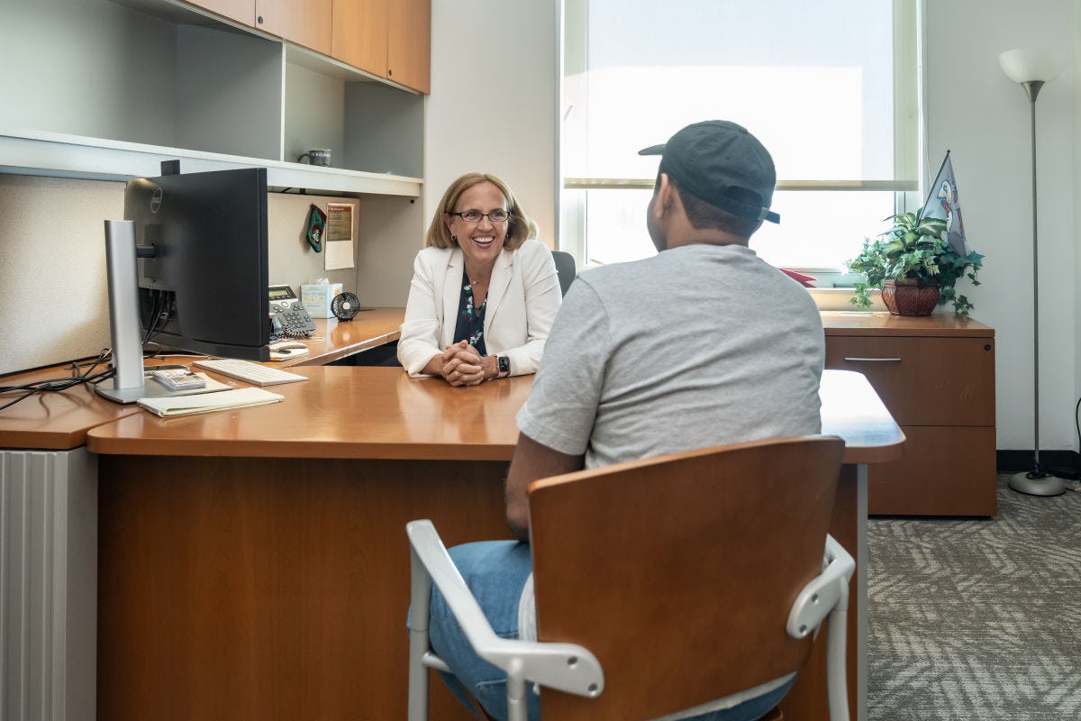 Michelle Crilly sits behind her desk talking to a student.