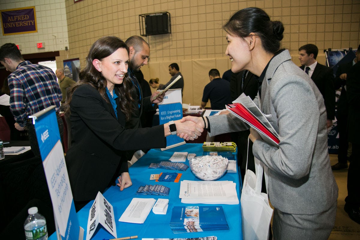 A recruiter and a Stevens student shake hands at a career event.