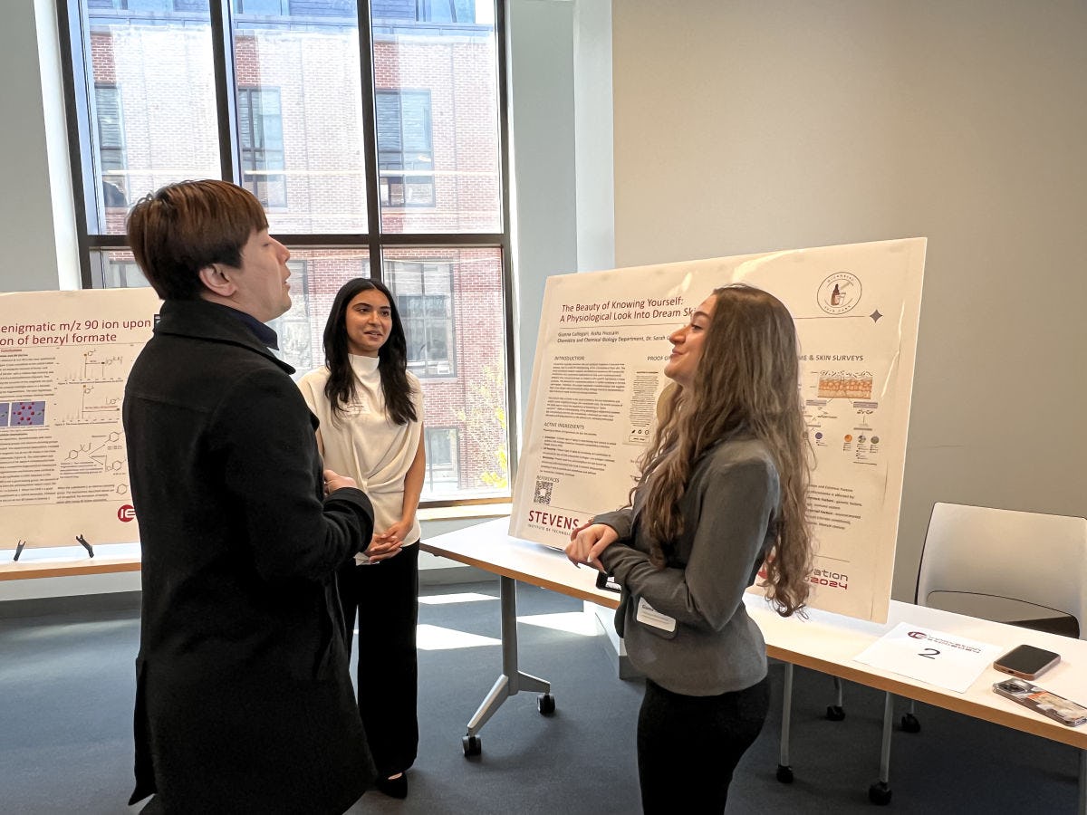 Students network among posters displaying presentations on poster boards.