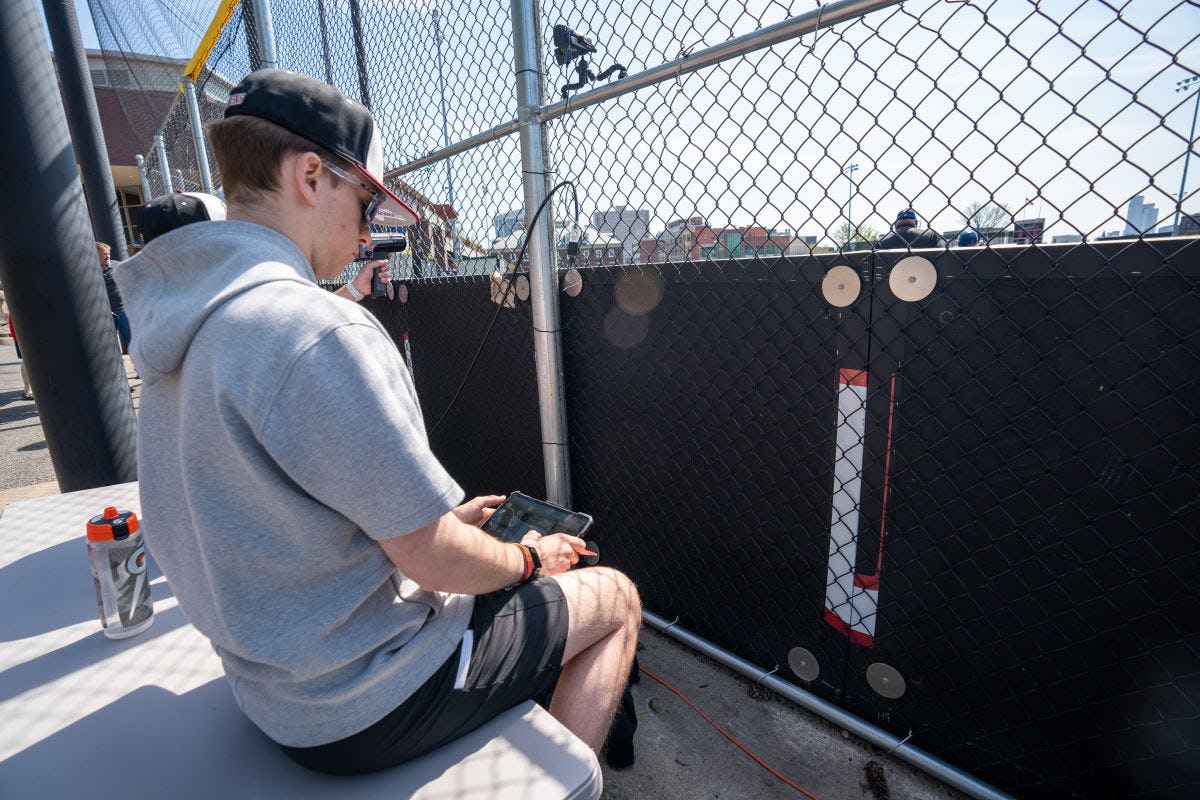Vaughn Weber sits behind the backstop at a Stevens baseball game inputting data into a tablet.