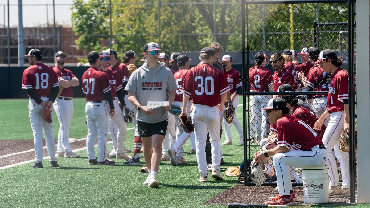 Vaughn Weber stands in the foreground of a group of Stevens baseball players on the field prior to a game.
