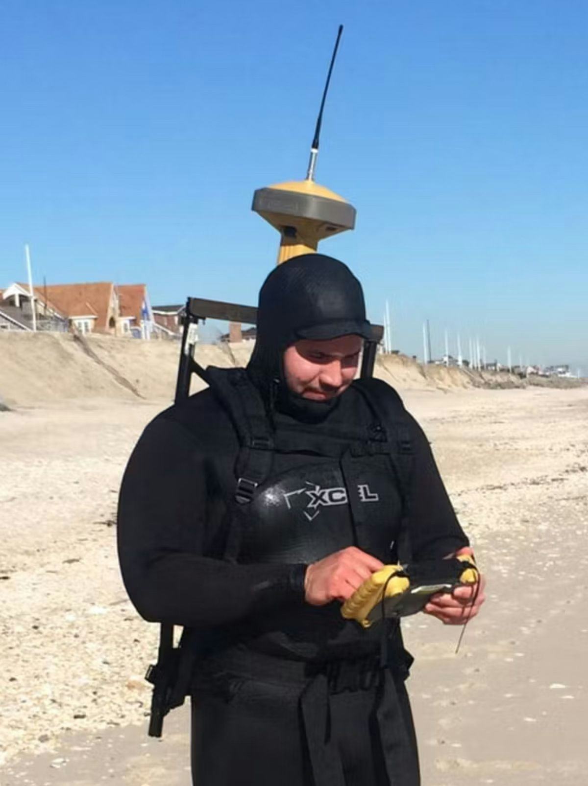 Student in wetsuit with tech gear on a New Jersey beach