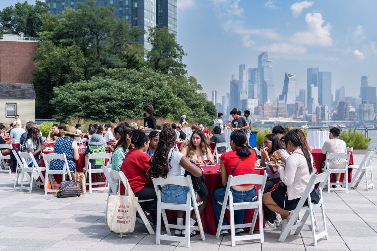 Students sit on the Babbio Center patio eating lunch.