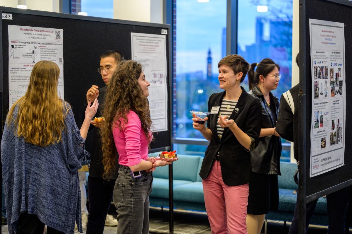 Two students in discussion during a social event and poster sessions at Stevens Institute of Technology.