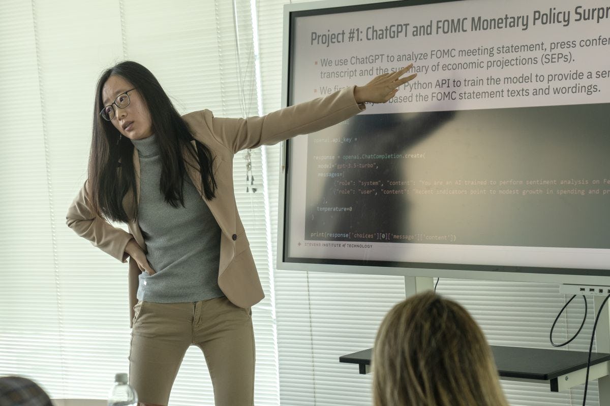 Victoria Li points to a smart board that reads ChatGPT and FOMC Monetary Policy