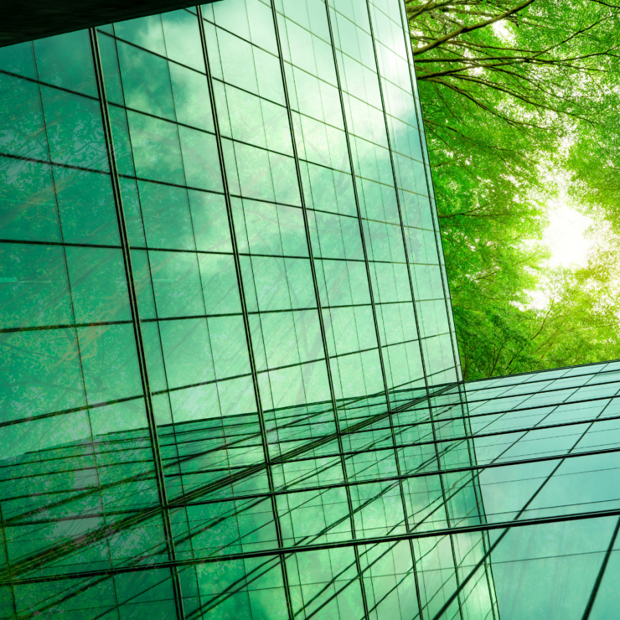 low-angle shot of a glass building, trees and the sky